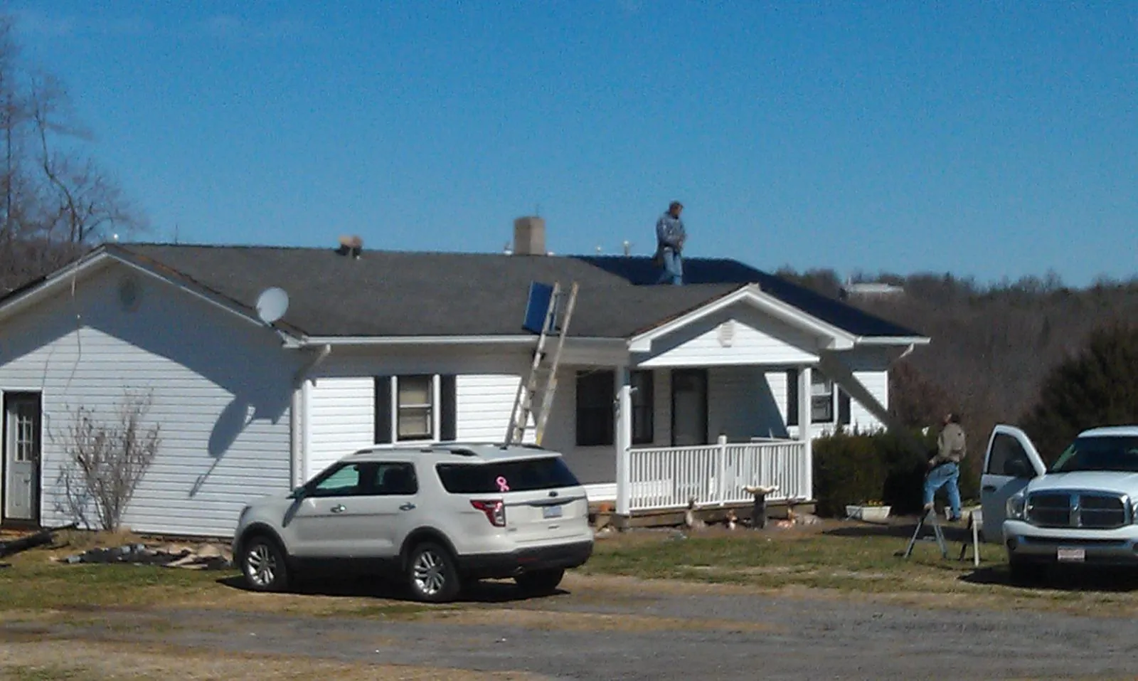 Roofers stripping shingles from a white ranch house roof in Springfield